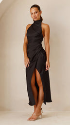 Woman wearing a black dress with a high slit on a beige background